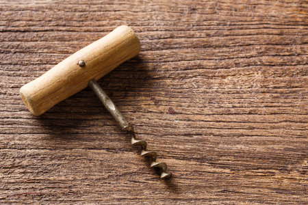 Close up old and rusty antique corkscrew opener on wooden table background