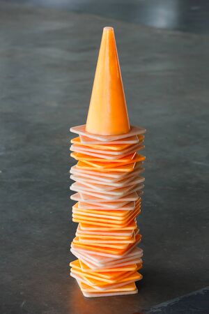 Close up stack of old and dirty orange color plastic traffic cones on concrete floorの写真素材