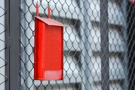 Close up old and rusty red color post box on wire netting fenceの写真素材