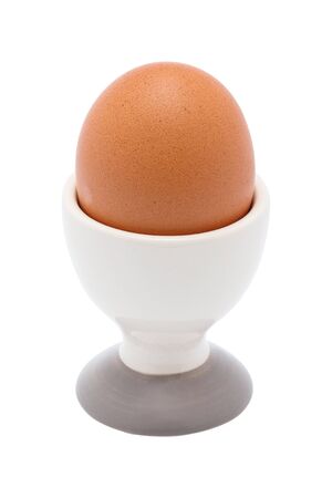 Boiled organic chicken egg in ceramic cup or holder isolated on whiteの写真素材