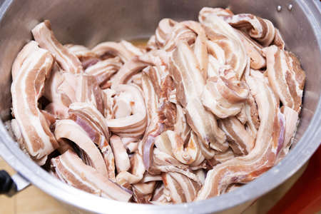 Closeup sliced pork belly in big pot preparing to cook, uncooked fresh meatの写真素材