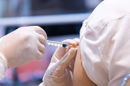 Closeup covid-19 vaccine injecting into patient arm shoulder with single use plastic syringe by doctor, Boost the immune system with inactivated or adenovirus virusの写真素材