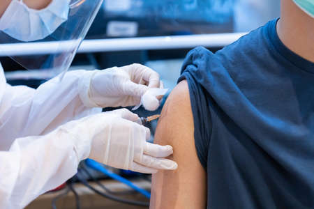 Closeup covid-19 vaccine injecting into patient arm shoulder with single use plastic syringe by doctor, Boost the immune system with inactivated or adenovirus virusの写真素材