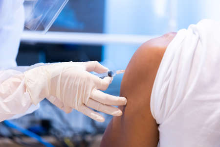 Closeup covid-19 vaccine injecting into patient arm shoulder with single use plastic syringe by doctor, Boost the immune system with inactivated or adenovirus virusの写真素材