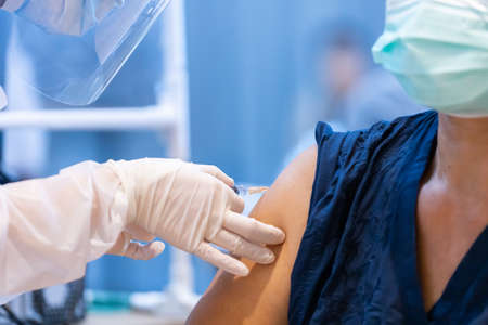 Closeup covid-19 vaccine injecting into patient arm shoulder with single use plastic syringe by doctor, Boost the immune system with inactivated or adenovirus virusの写真素材