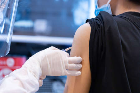 Closeup covid-19 vaccine injecting into patient arm shoulder with single use plastic syringe by doctor, Boost the immune system with inactivated or adenovirus virusの写真素材