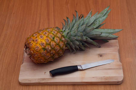 Pineapple with a knife on a chopping boardの写真素材