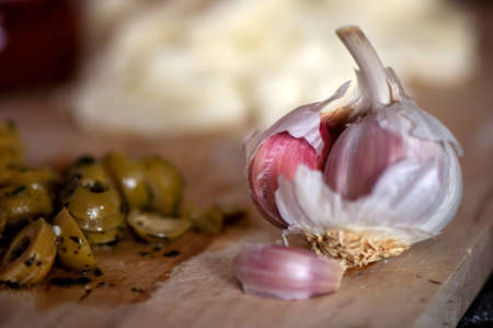 A garlic clove on a chopping board along with other italian ingredientsの写真素材