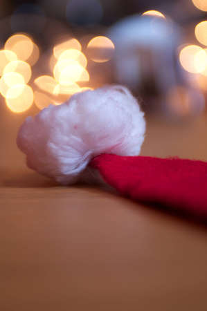 Father Christmas's hat lying on a table with twinkling christmas lights in the backgroundの写真素材
