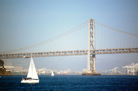 A Boat sailing past the Bay Bridge in San Francisco Bay, California