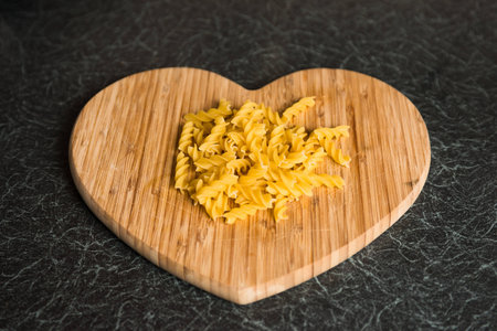 White Wheat Fusilli Pasta on Heart Shaped Chopping Boardの写真素材