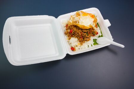 Rice topped with stir-fried pork and basil on foam boxの写真素材