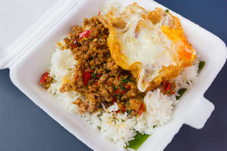 Rice topped with stir-fried pork and basil on foam boxの写真素材