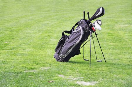 Black golf bag on green grass as a backgroundの写真素材