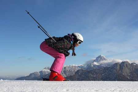 The young girl on skis in the background of mountains covered with snowの写真素材