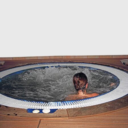 A young woman relaxing in pool and enjoys the water bubbleの写真素材