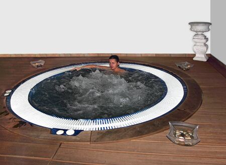 A young woman relaxing in pool and enjoys the water bubbleの写真素材