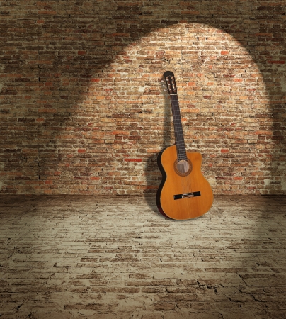 Old wooden guitar leaning against the brick wallの写真素材