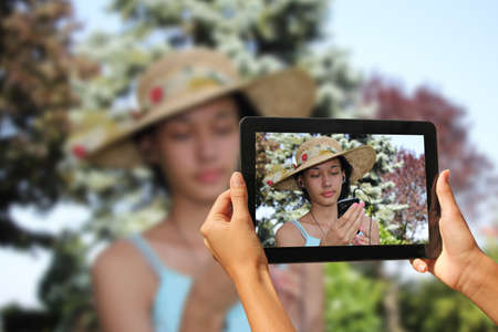 Beautiful young girl, listening to music while being photographed with tabletの写真素材