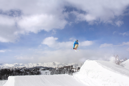 Jumping skier at jump inhigh mountains at sunny dayの写真素材