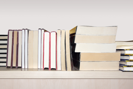 A pile of different books on a wooden shelfの写真素材