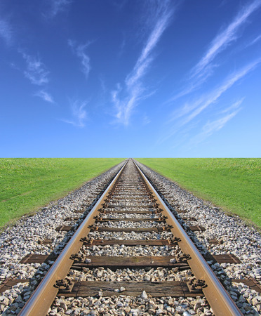 Railway track, green grass and blue sky on the horizonの写真素材
