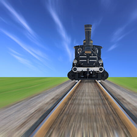 An old steam powered locomotive, railway track, green grass and blue sky blurredの写真素材