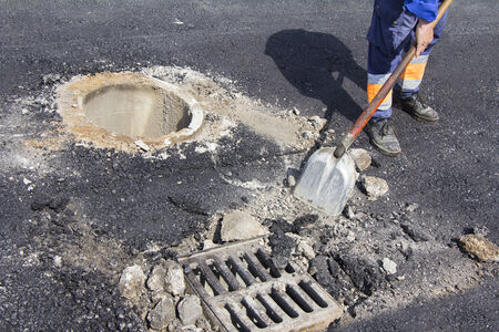 Utilities worker repairing sewer manhole cover in the roadの写真素材