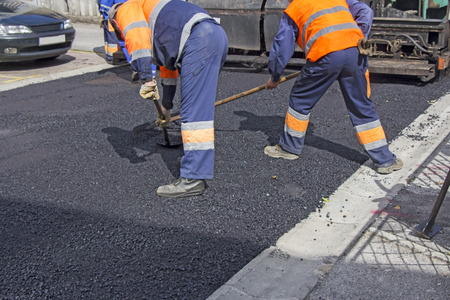 Workers on Asphalting paver machine during Road street repairing worksの写真素材