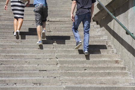 A woman and two man climbing on concrete stairsの写真素材