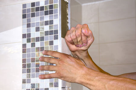 Worker puts tiles in the wall bathroom の写真素材