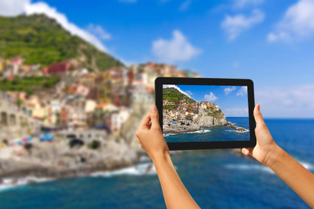 Girl taking pictures on a tablet in Manorola, Cinque Terre, Italyの写真素材