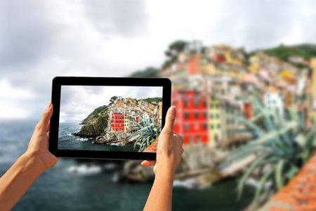 Girl taking pictures on a tablet in Riomaggiore, Cinque Terre, Italyの写真素材
