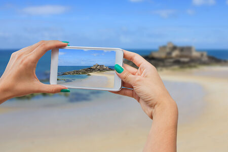 Girl taking pictures on a mobile phone in the Fort on island Petit Be in Saint-Malo,  Normandy / Brittany, Franceの写真素材