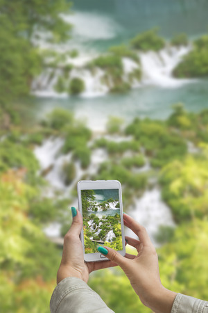 Girl taking pictures on a cellphone in Plitvice Lakes National Park in Croatiaの写真素材