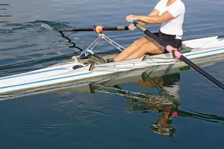 A young rower in a boat, paddles on the tranquil lakeの写真素材