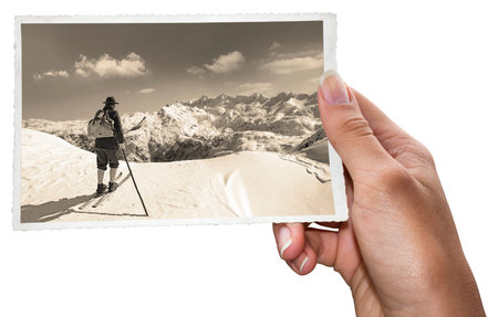 A woman holding old photos of skier with traditional old wooden skis