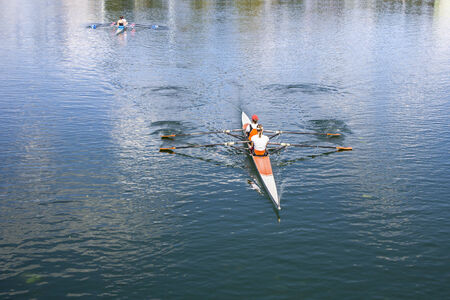 Two Women Rower in a boat, rowing on the tranquil lakeの写真素材
