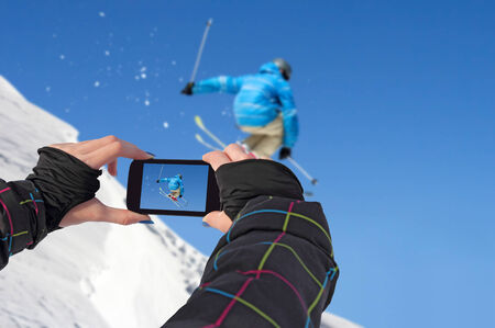 A young girl by mobile phone photographed of skiers jumpの写真素材