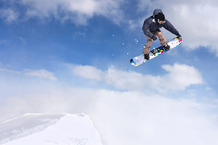 Jumping snowboarder through air on blue sky background