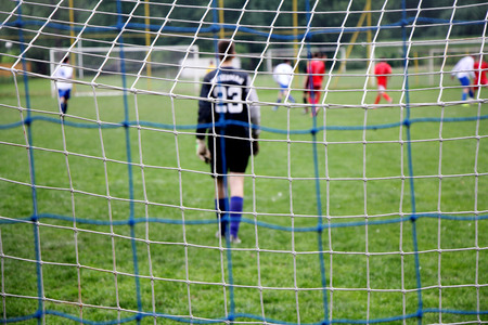 Soccer goal mesh with football players in action background soft focusの写真素材