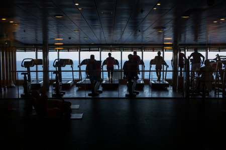 People exercising at the gym on a cruise ship in silhouette on sea backgroundの写真素材