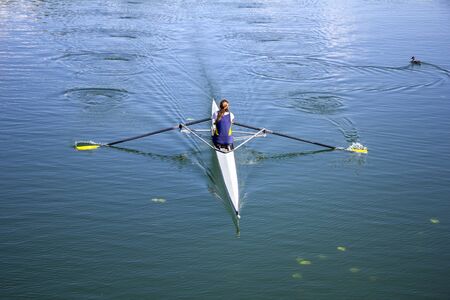 Young girl rower training rowing on the lake, to her wild duckの写真素材