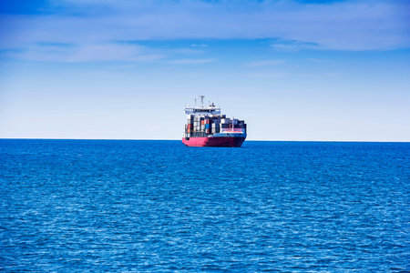 Tugboats pulling container cargo ship to harbor