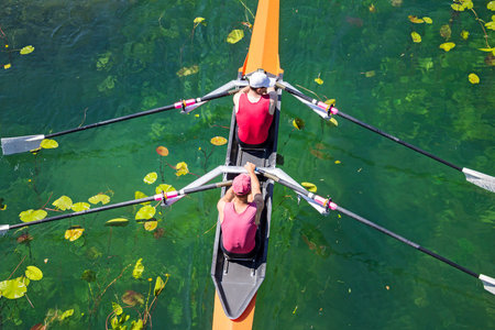 Two rowers in a boat, rowing on the tranquil lake