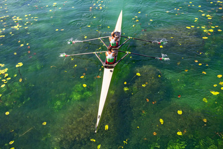 Two rowers in a boat, rowing on the tranquil lake