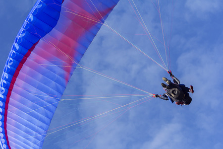 Tandem Paragliding on background of blue summer sky and white cloudsの写真素材