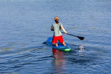 Man on Paddle Board paddling out to lake
