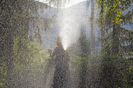 A young woman Watering a lawn in the yard of the house, a background sunlightの写真素材