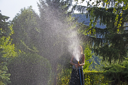 A young woman Watering a lawn in the yard of the house, a background sunlightの写真素材